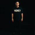 Person wearing a black t-shirt with 'MONEY' printed in white on a dark background