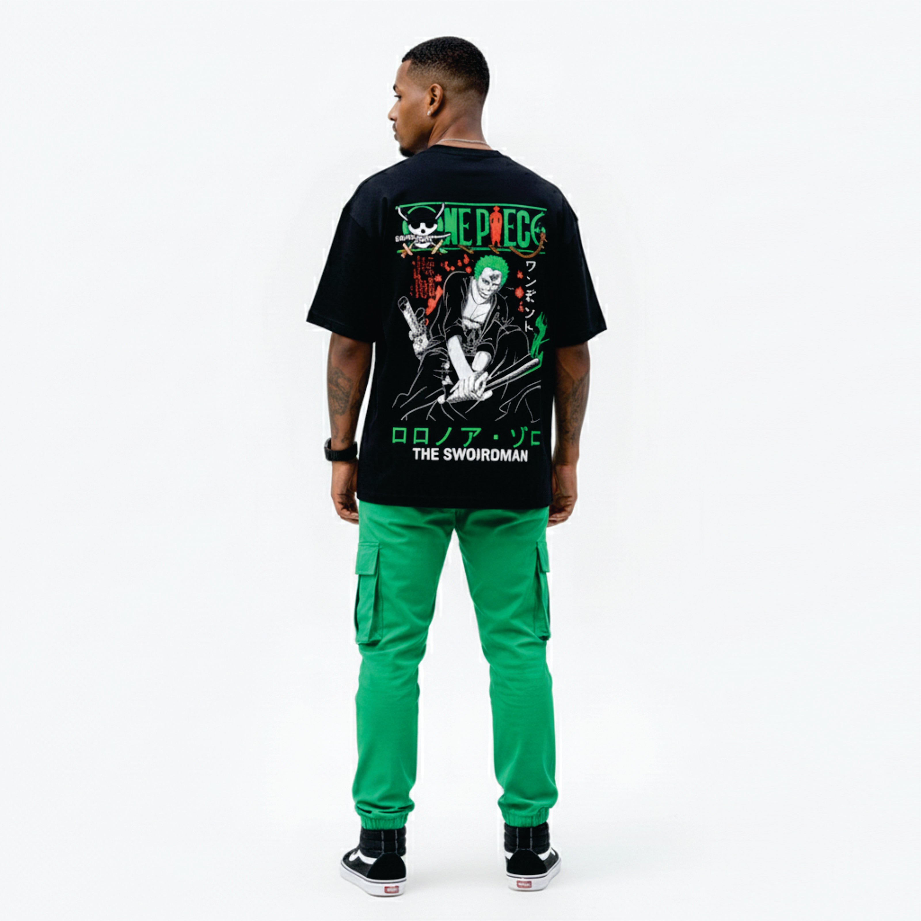Person wearing a black t-shirt with graphic design and green pants on a white background