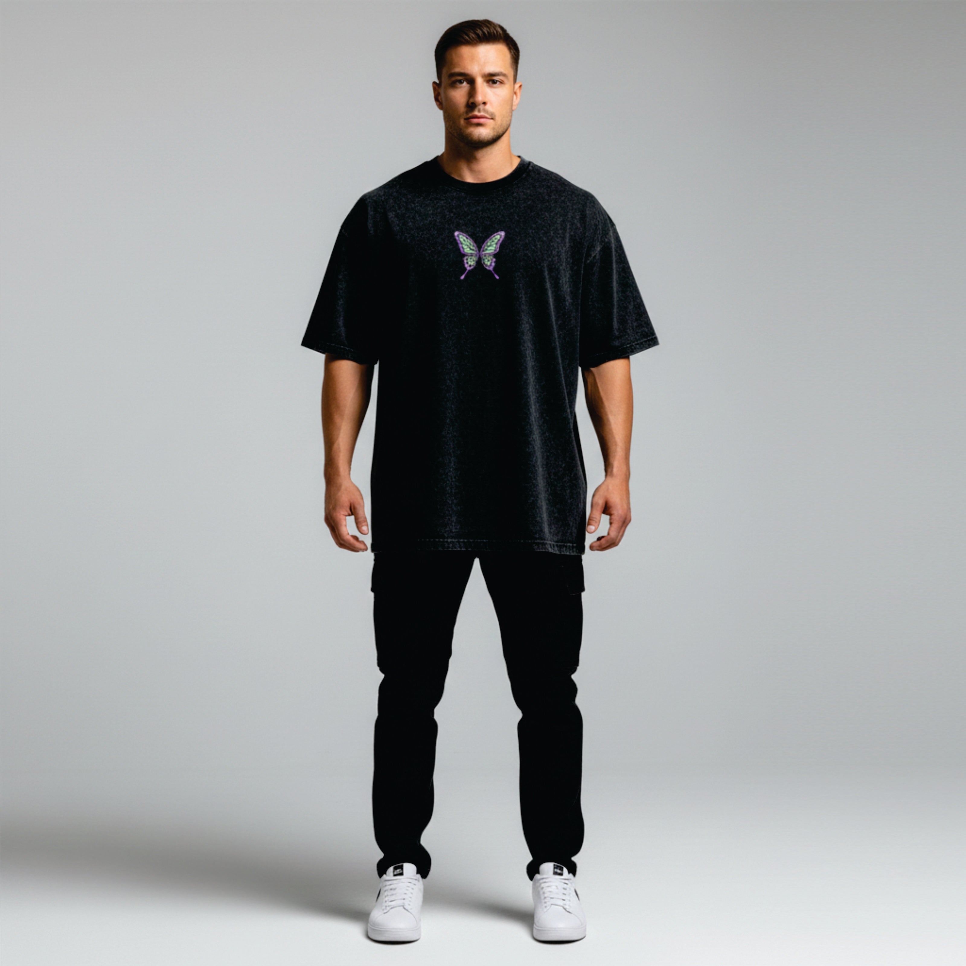 Man wearing a black t-shirt with a butterfly design on a plain background