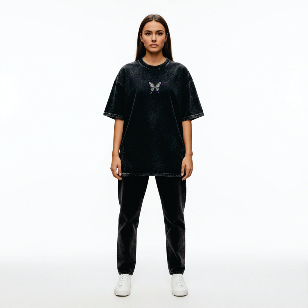 Person wearing a black oversized t-shirt with a butterfly design on a white background
