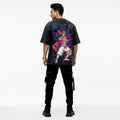 Person wearing a black t-shirt with colorful graphic design on the back, standing against a white background