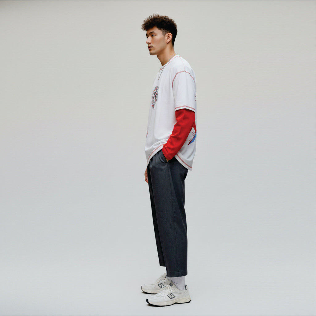 Person wearing a white and red long-sleeve shirt with dark pants on a light gray background