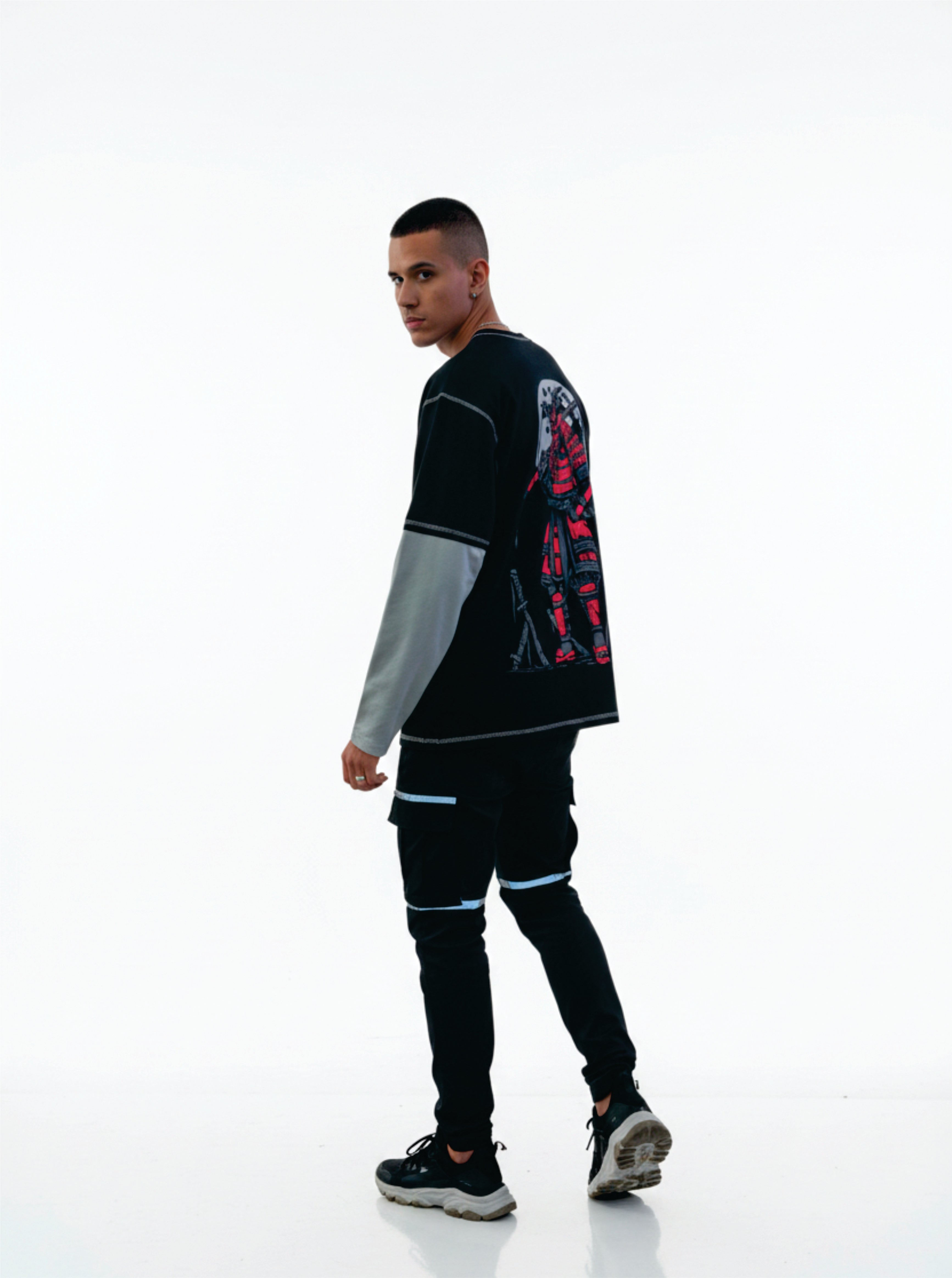 Person wearing a black and gray outfit with colorful designs on a white background