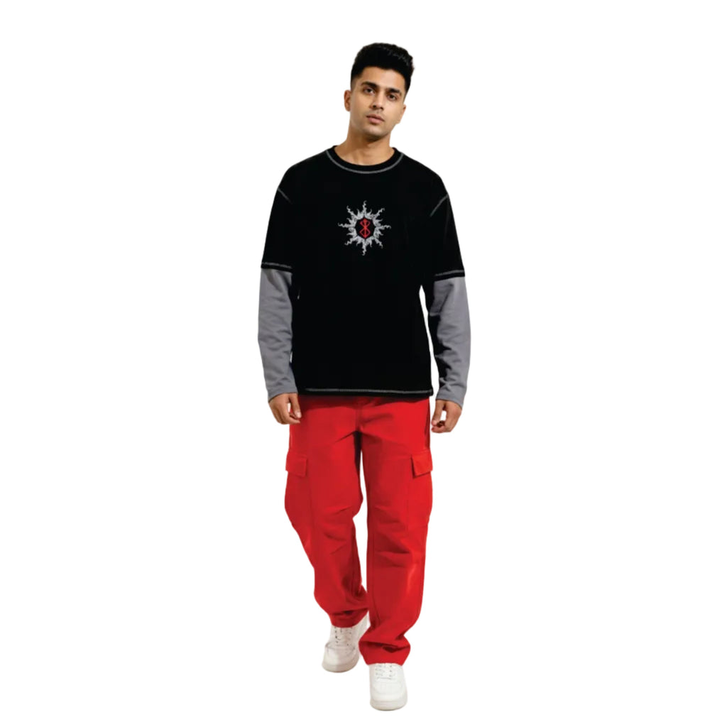 Man wearing a black and gray sweater with a red design and red pants on a white background