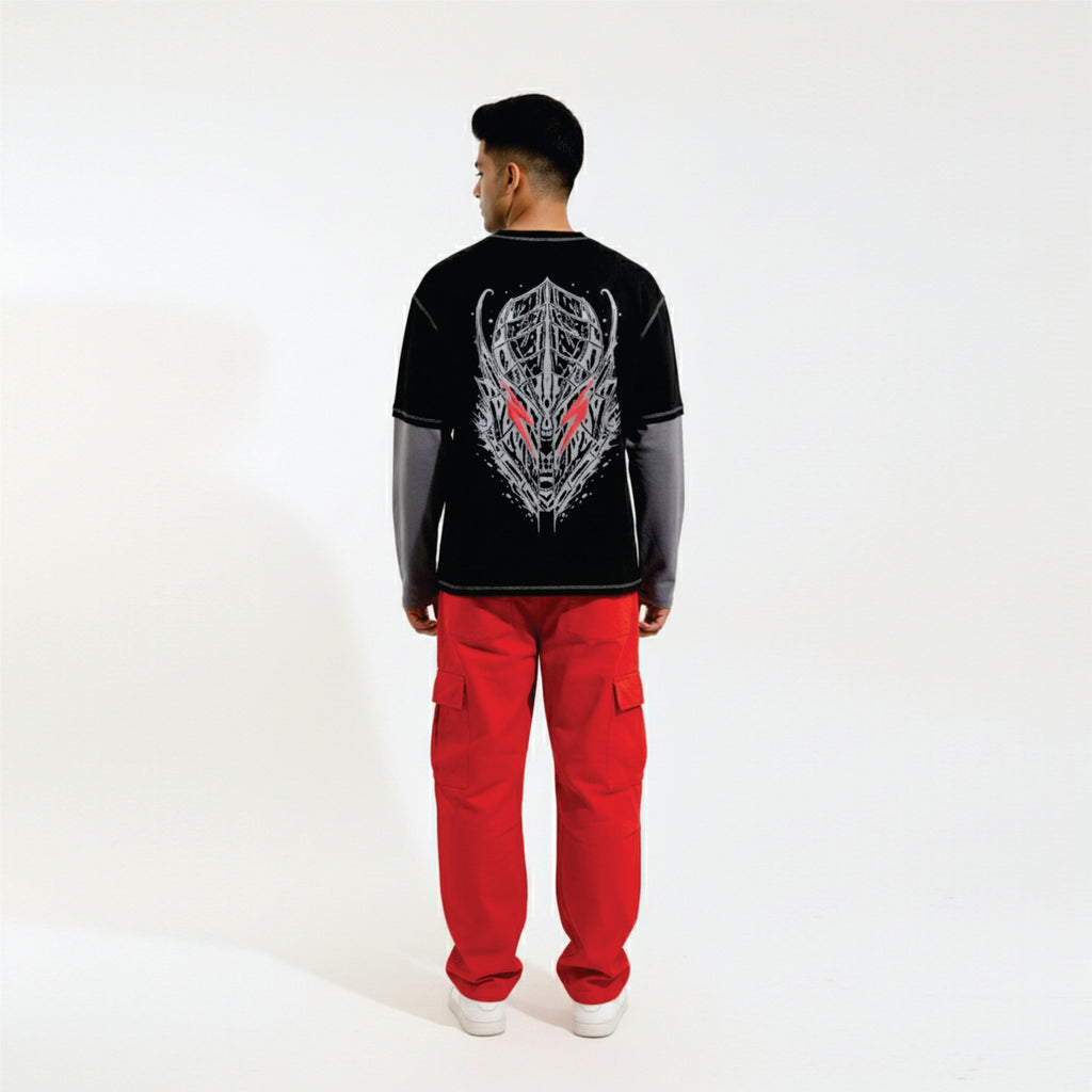 Person wearing a black long-sleeve shirt with a graphic design and red pants on a white background
