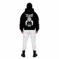 Person wearing a black hoodie with white text and graphics on the back, standing against a white background.